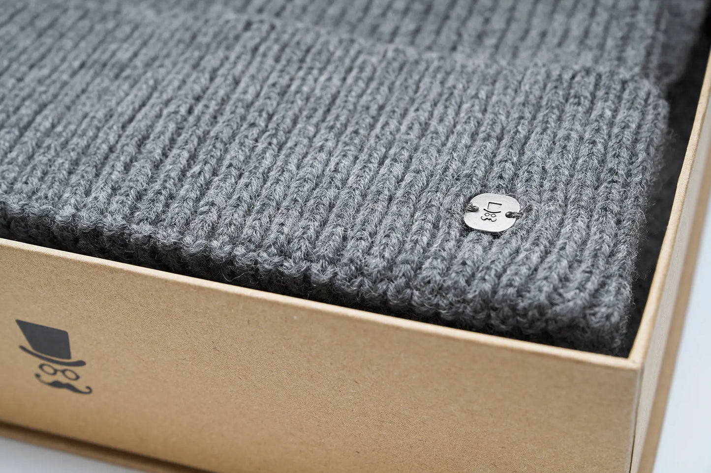 (Grau) Herrenschal Mütze Set Wolle – Detailansicht Logo-Pin in Box